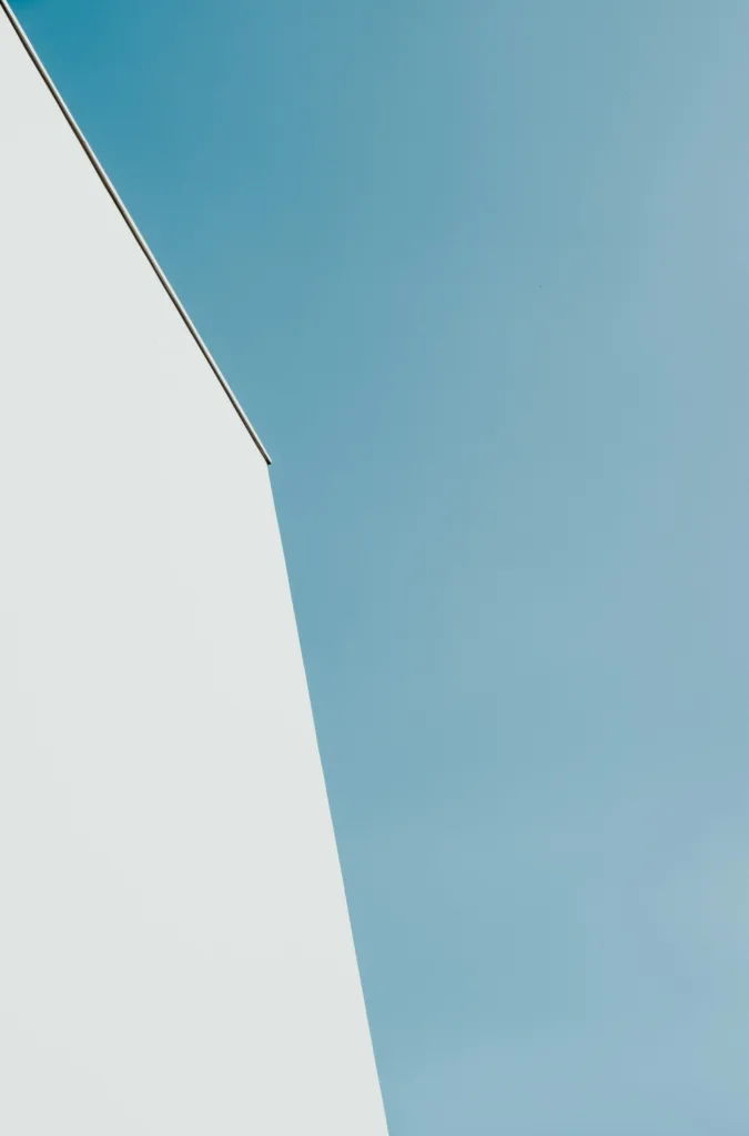 Minimalist white building edge against a clear blue sky