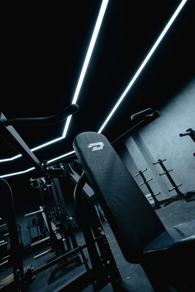 Modern gym interior with black exercise machines and bright geometric ceiling lights
